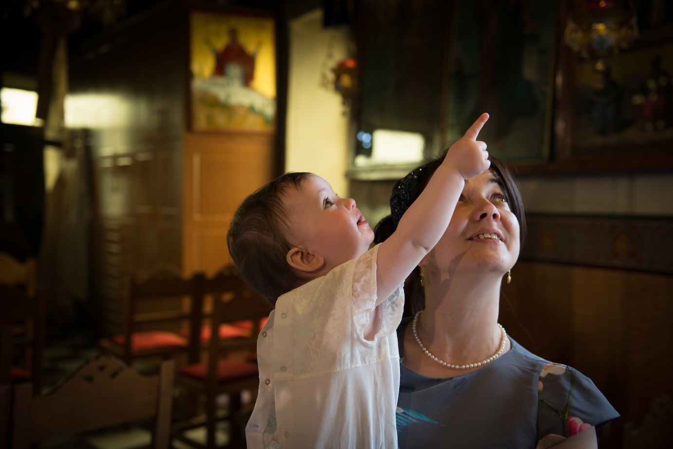 A happy baby hugging their godmother during a Greek baptism.