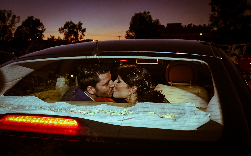 Newlyweds sharing a kiss in a car.